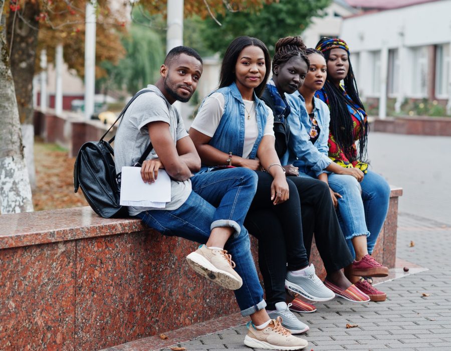 Group of five african college students spending time together on campus at university yard. Black afro friends studying. Education theme.