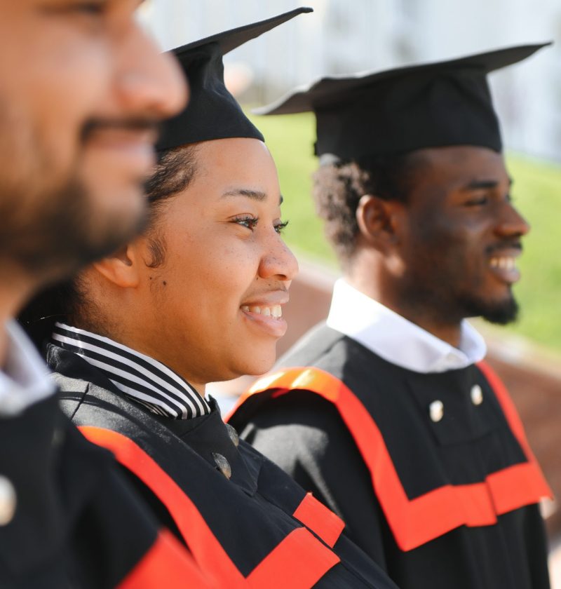 education, graduation and people concept - group of happy international students in mortar boards and bachelor gowns with diplomas.