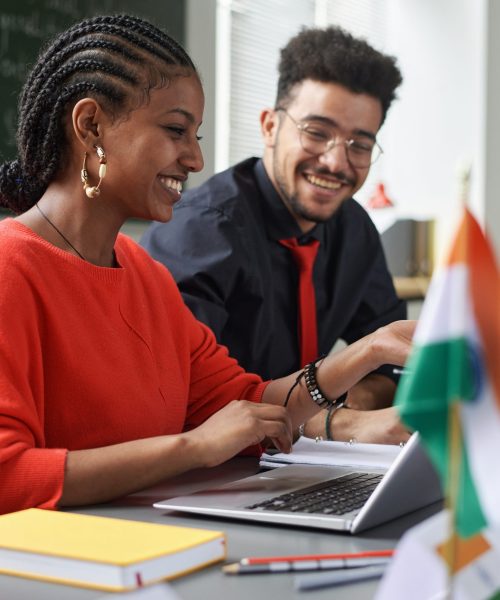 Two young students man and woman working on project together in multicultural school classroom, copy space