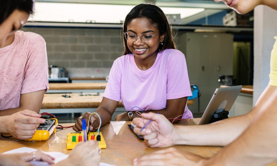 Multiracial students learning electronic at technology lesson - Group of teenager people building and programming electric circuits together in classroom